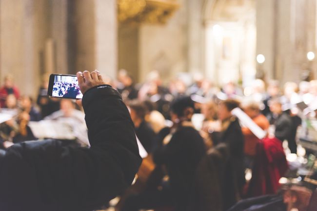 Pessoa gravando uma orquestra em um smartphone