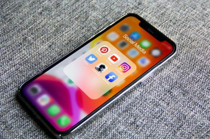 Iš arti išmaniajame telefone su socialinių tinklų piktogramomis ekrane.