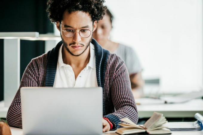 Um estudante universitário usando um laptop durante a aula. 