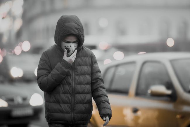 大気汚染から保護するために呼吸マスクを着用している都市の若者。