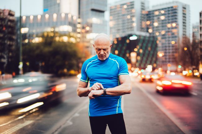 彼のスマートウォッチのトラフィックに立っている男。