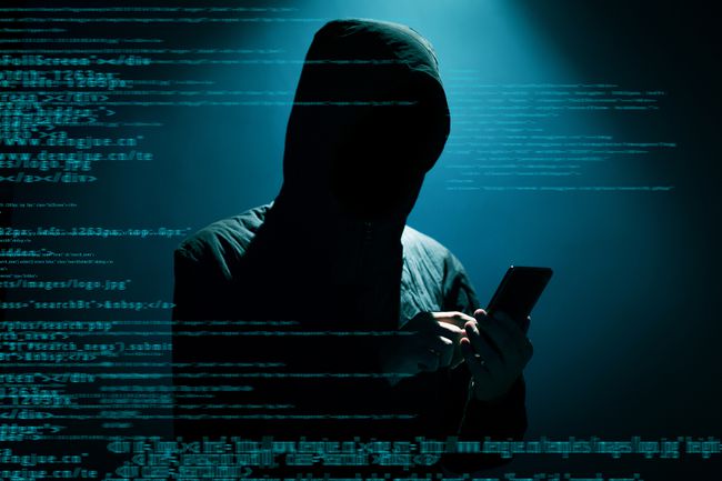 Hacker usando smartphone com código sobreposto à imagem. 