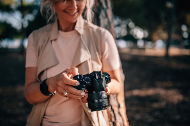 Žena koristi kameru i gleda fotografije u prirodi