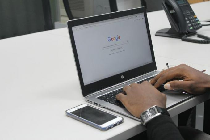 Alguém usando a Pesquisa Google em um laptop em uma mesa de conferência. 