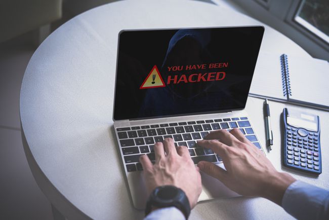 Nærbillede af hacker, der bruger bærbar computer på bordet