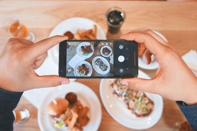 スマートフォンで食べ物の写真を撮っている人。