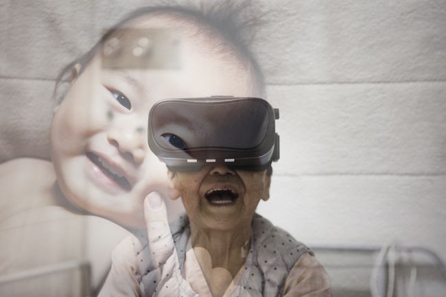 Vanhus vuorovaikutuksessa lapsen virtuaalisen kuvan kanssa VR-laseja käyttäessään.