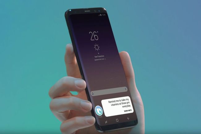 Kädessä Samsung-puhelin, jonka näytöllä on Bixby