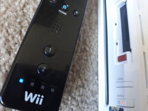 WiiリモコンのLEDがWiiの赤い同期ボタンの横で点滅しています。