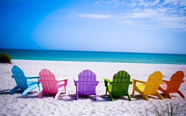 Papel tapiz de playa gratuito con sillas de colores en una playa de arena blanca