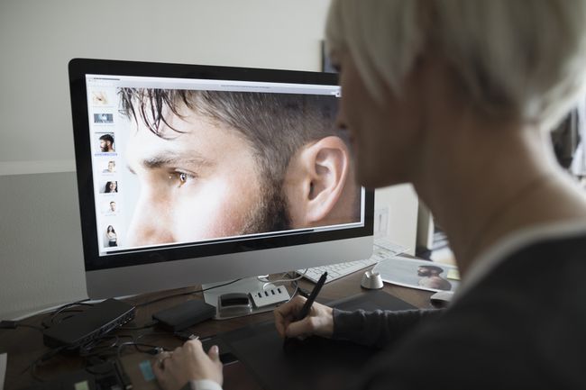 Weibliche Bildbearbeiterin mit Grafiktablett, Bearbeitung digitaler Fotos auf dem Computer im Büro