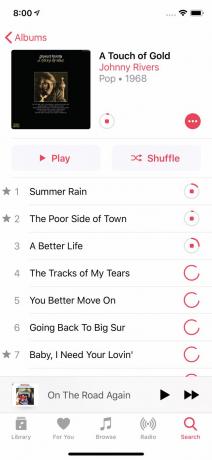 En skärmdump av låtar som laddas ner i Apple Music på iPhone