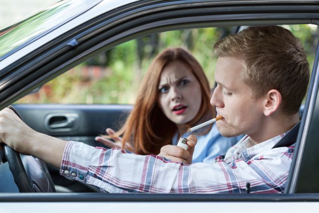 Een chauffeur steekt een sigaret op in een auto.