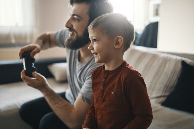 Niño feliz jugando juegos de computadora con su padre en casa