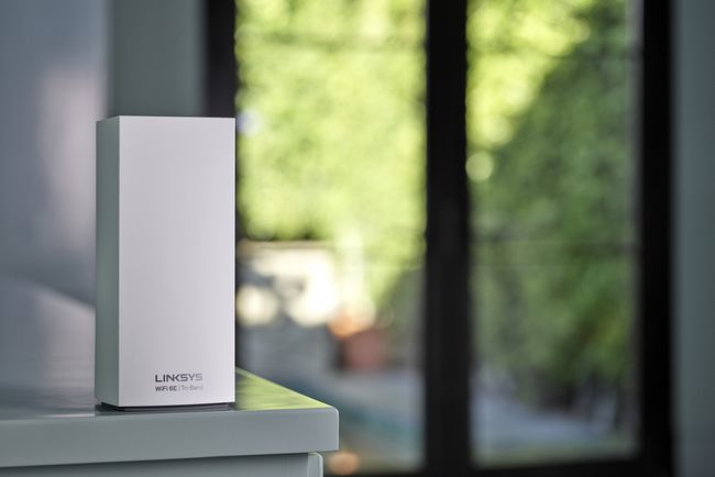Le nœud de réseau maillé Linksys Atlas Max 6E sur une table devant une porte coulissante.