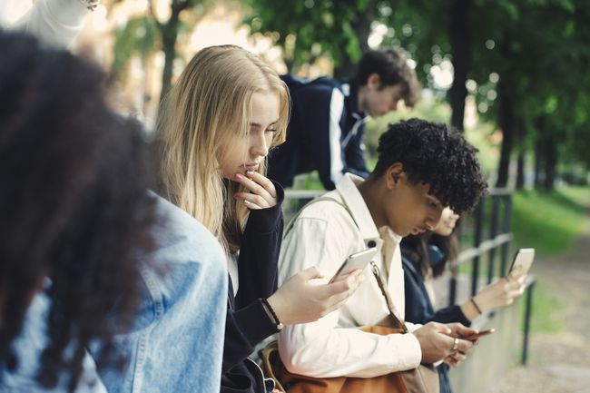 公園でスマートフォンを使用している10代の若者のグループ。