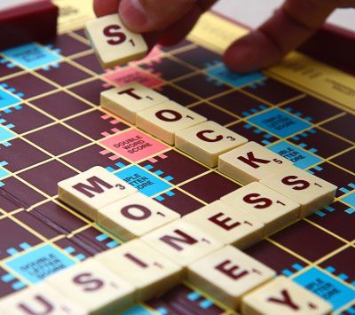 Roka položi črkovno ploščico na ploščo Scrabble