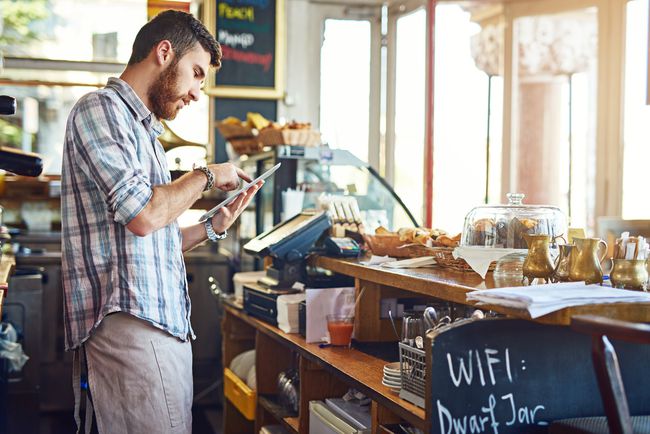 iPadを使用して喫茶店で働く男