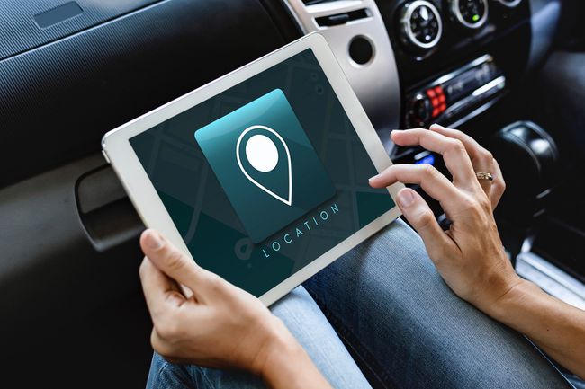 Eine Person, die mit einem Tablet in einem Auto sitzt, verwendet eine GPS-Ortungs-App.