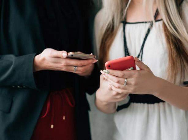 Duas pessoas juntas transferindo informações de contato por meio de seus smartphones.