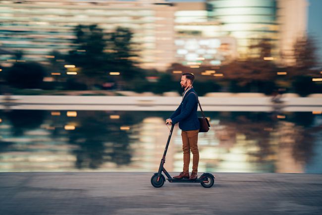 市内の水路でスタンドアップ型電動スクーターに乗るビジネスパーソン。