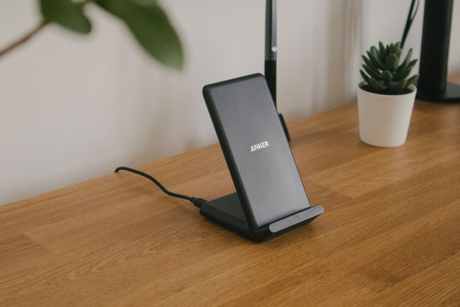 茶色の木のテーブルに置かれた黒の Anker 電話充電ドック