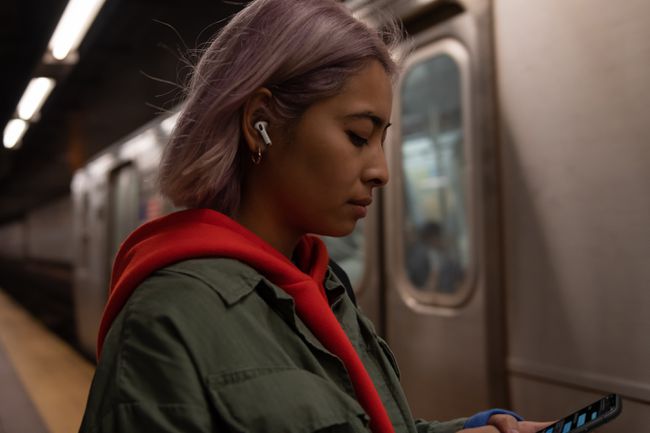 Valaki felszáll egy vonatra, miközben Apple AirPods készüléket visel.
