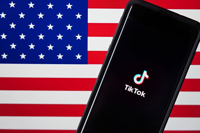 TikTokアプリを搭載した携帯電話がアメリカの国旗の横に表示されます