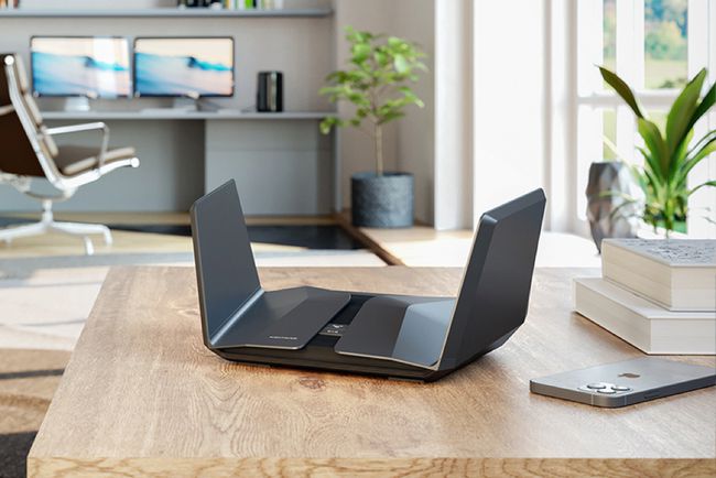 Un routeur Netgear Nighthawk sur un bureau avec un smartphone à proximité.