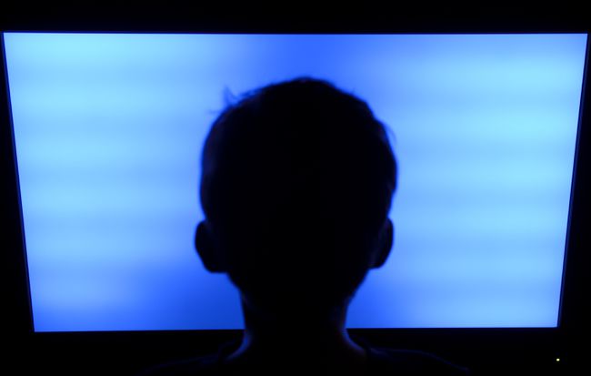 Силуэт головы ребенка перед телевизором с плоским экраном
