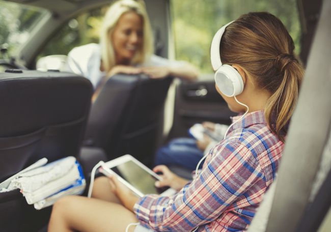 Mellomskoleelev lytter til hodetelefoner i en bil.