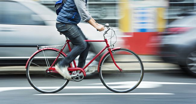 動きのある通りで赤い自転車でサイクリングする人