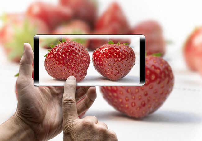 Foto av en smartphone som tar ett foto av jordgubbar