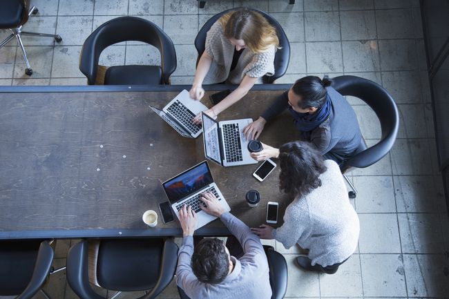 Un grupo de personas que trabajan en una mesa en portátiles.