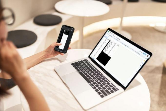 Uma pessoa olhando a mesma planilha em um telefone e em um MacBook