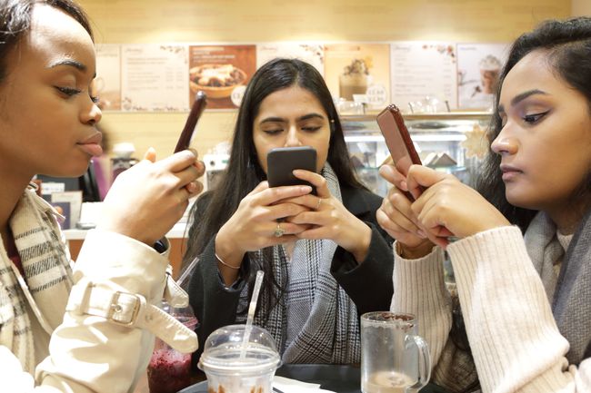 Trei tineri la telefoane în cafenea