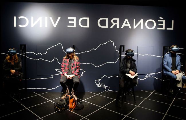 Посетители надевают гарнитуру виртуальной реальности (VR), просматривая виртуальную и интерактивную анимацию во время пресс-визита на выставку «Леонардо да Винчи» в Лувре.