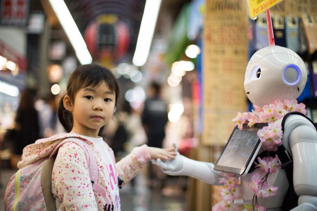 にぎやかな市場でロボットの手を握っている子供。