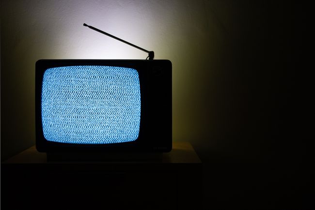 TV 화면에 정적이 있는 희미한 조명이 있는 방에 있는 오래된 아날로그 TV.