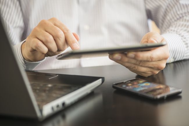 Cerca del hombre que usa varios dispositivos móviles: teléfono, mesa y computadora portátil