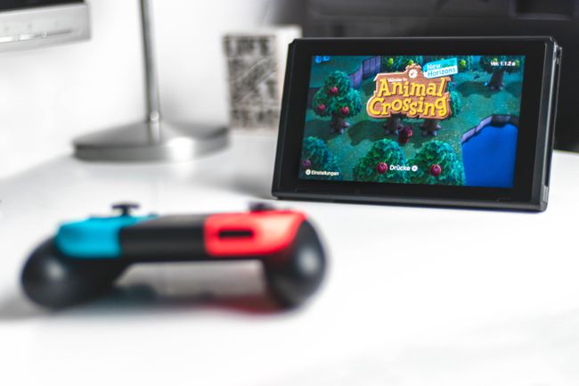 白い背景に別のコントローラーを搭載したNintendoSwitchタブレット、どうぶつの森が画面に表示されます。 