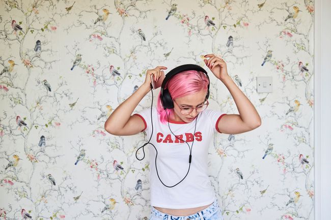 Persona con i capelli rosa che ascolta la musica.