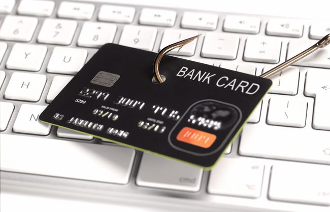 Gambar konsep keamanan kartu kredit dengan kail ikan yang diletakkan di atas papan ketik komputer.
