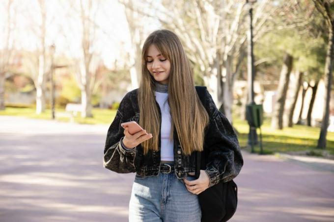 Um estudante andando lá fora enquanto olha para um telefone