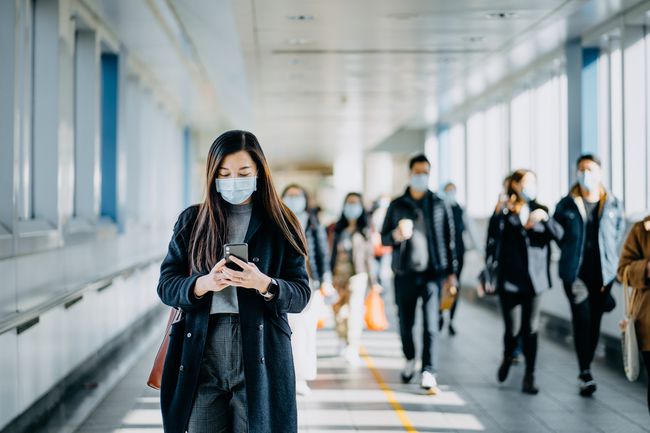 Frau überprüft Telefon mit Maske auf