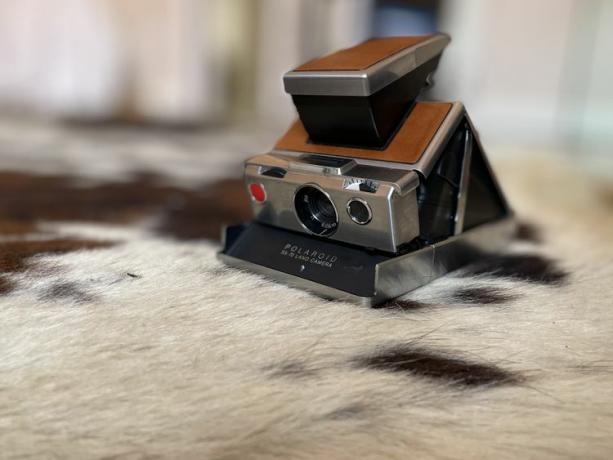 „Polaroid SX-70“ antžeminė kamera atidaroma ant karūninio kilimėlio