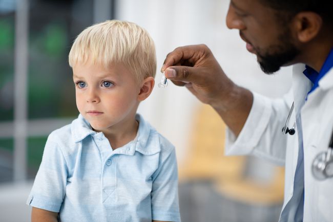 Лікар-аудіолог встановлює дитині слуховий апарат.