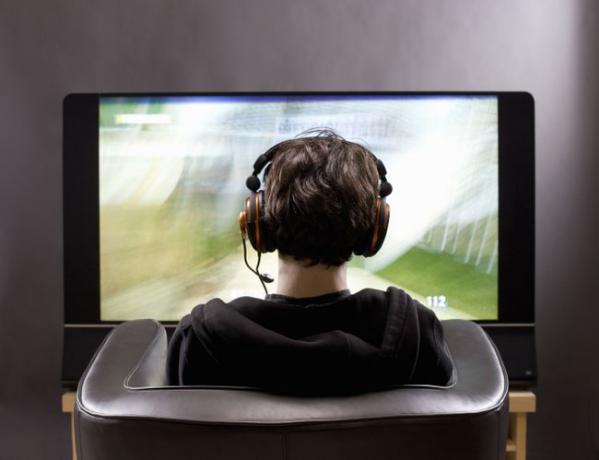 10대 소년이 비디오 게임을 하는 TV 앞에 앉아 있다