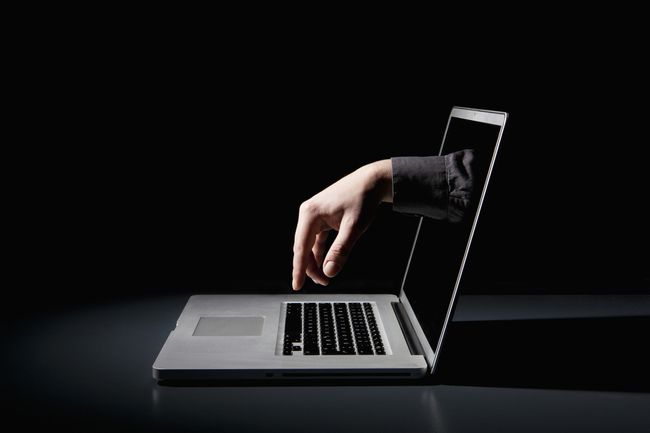 En hånd rækker gennem en bærbar computer for at skrive på tastaturet