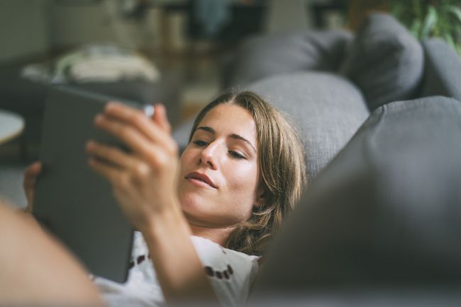 Eine Frau mit einem iPad auf einer Couch.